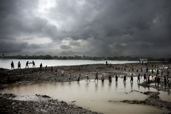 Bangladesh flood defences: Men stand in line, sending mud up to the embarkment