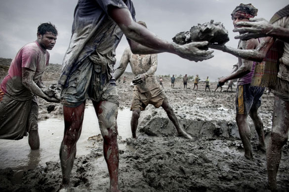 Bangladesh flood defences: Men pass mud along a line