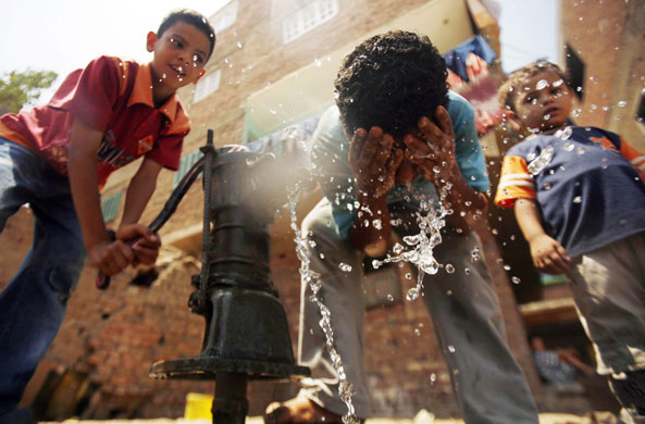 24 hours: Egyptian children drink and wash in water from a hand pump  