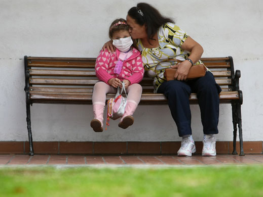 24 hours: Osasco, Brazil: A girl with flu symptoms is comforted 