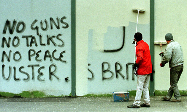 Peace walls in Belfast: Painters whitewash over political graffiti on the Peace Wall 