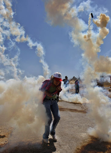 24 hours in pictures: A foreign demonstrator runs as tear gas fired by Israeli troops