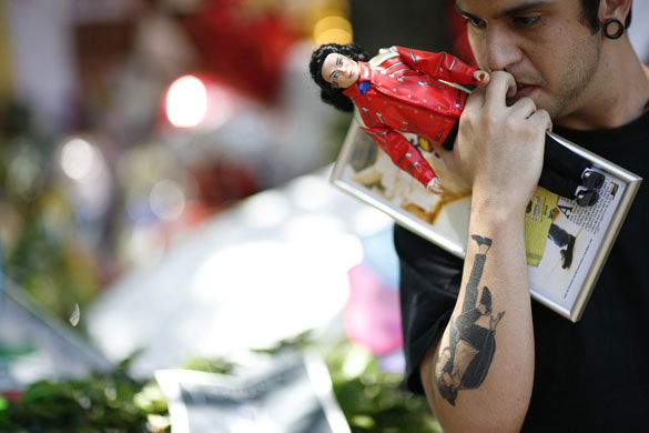 24 hours in pictures:  A fan holds a doll and a framed photo of deceased pop star Michael Jackson