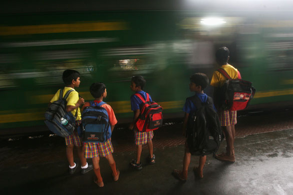24 hours in pictures: Schoolchildren wait for a train to stop at a railway station in Mumbai