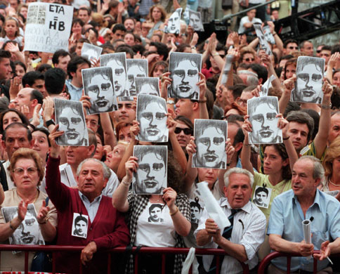 History of ETA: 1997: Spaniards in Madrid hold up pictures of Miguel Angel Blanco Garrido