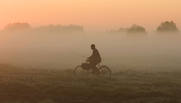 24 hours: Fisherman rides a bicycle during a foggy in 