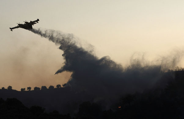 24 hours: A fire-fighting airplane drops water over a forest fire in greece