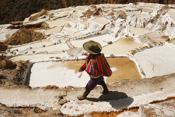 24 hours in pictures: Cuzco, Peru: A woman walks through pools of salt at the Maras mines