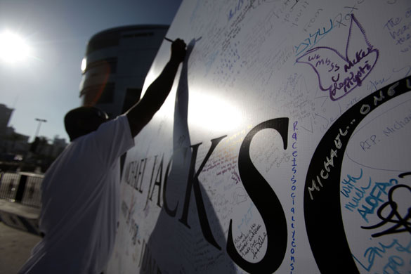24 hours in pictures: Los Angeles, California, USA: A man signs a large MIcahel Jackson poster