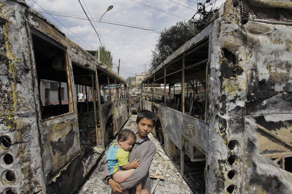 Urumqi riots: Children walk past burnt out buses