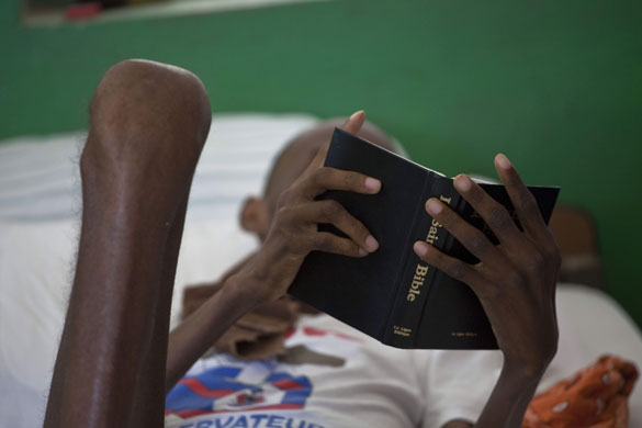24 hours in pictures: A patient with HIV/AIDS, reads the bible at the St. Nicolas hospital Haiti