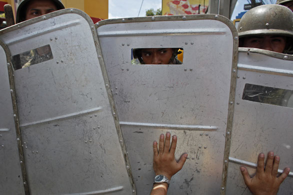 24 hours in pictures: Supporters of Honduras President sit in front of a line of soldiers