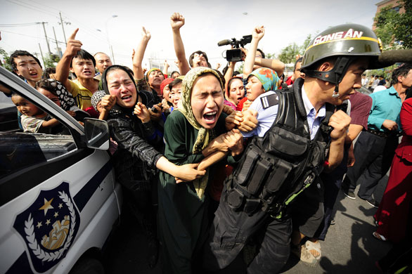 24 hours in pictures: Ethnic Uighur women grab a riot policemen as they protest in Urumqi
