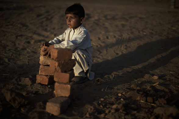 24 hours in pictures: A young Pakistani boy, internally displaced from Swat, gathers bricks