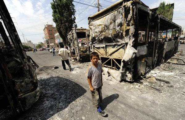 24 hours in pictures: A boy stands amidst the burnt wreckage of a bus in Urumqi