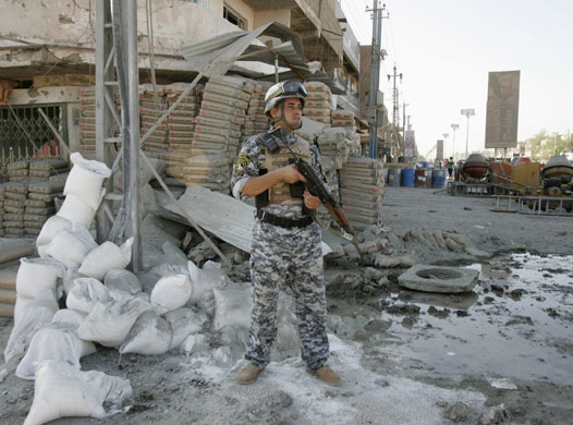 Iraq bombings: A policeman stands guard at the site of a bomb attack