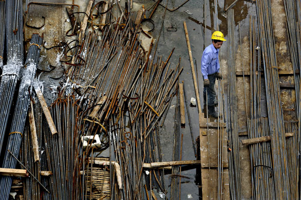 12 August 2009: Shanghai, China: A worker holds steel rods at a construction site