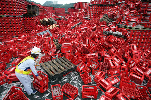 12 August 2009: Yaizu, Japan: A factory worker cleans up broken bottles after an earthquake