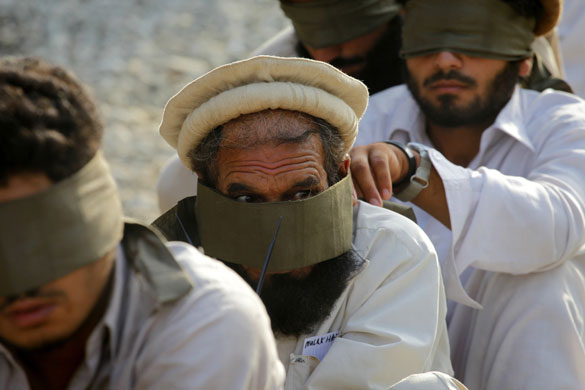 14 August 2009: Pesh valley, Afghanistan: A man peers out from a loose blindfold