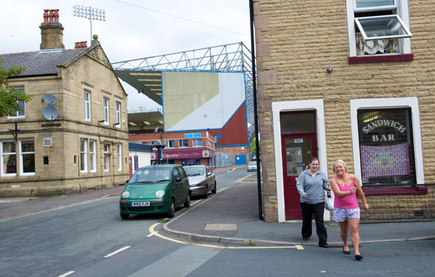 Burnley Premier League: Two local residents stroll past the Clarets Sandwich shop behind Turf Moor.