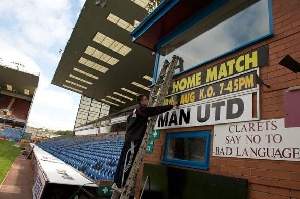 Burnley Premier League: A member of the Turf Moor staff adjusts a sign 