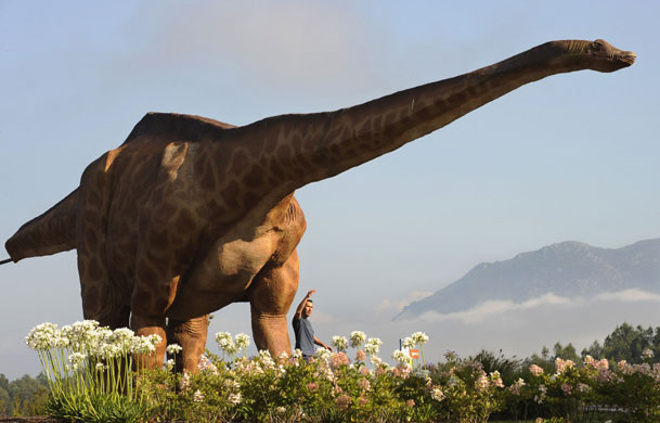 24 hours in pictures: Colunga, Spain: A man poses next to a dinosaur model