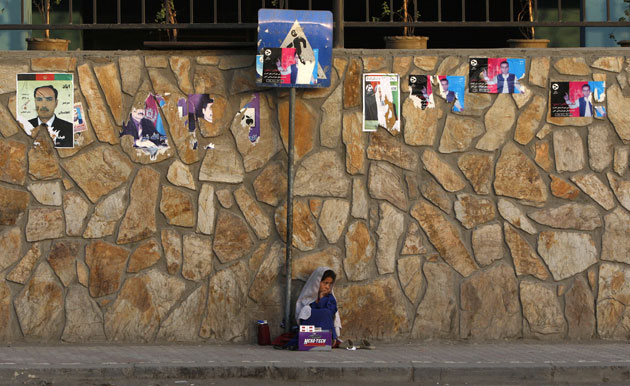 24 hours in pictures: Kabul, Afghanistan: Girl sitting under election posters sells cigarettes  