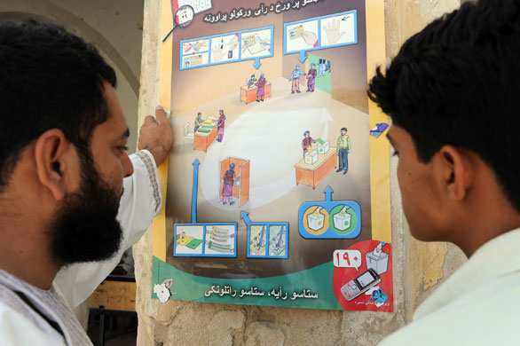 Afghanistan elections: Kandahar: Men look at a poster showing how to cast their vote 