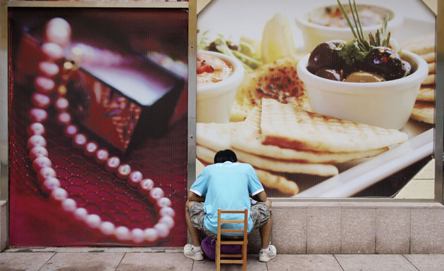 24 hours in pictures: A man eats in front of advertisements food and jewelry  in Beijing 