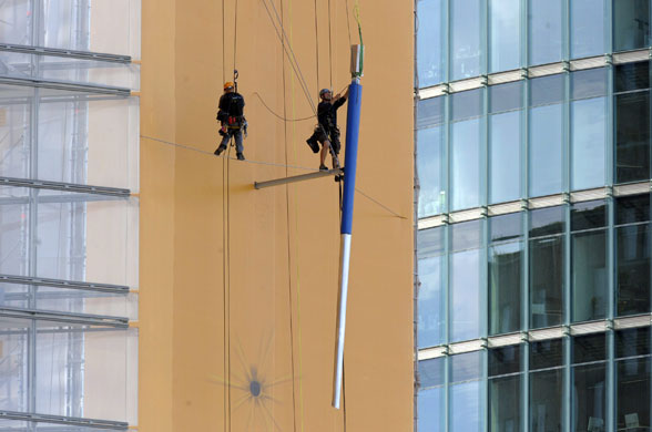 24 hours in pictures: Berlin, Germany: Workers on ropes attach a section of a huge javelin