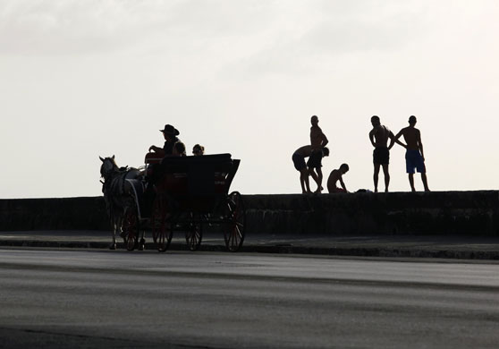 24 hours in pictures: Havana, Cuba: Tourists ride in a horse-drawn cart along the seafront 