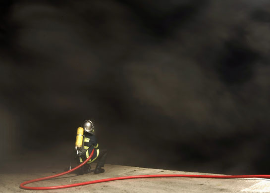 24 hours in pictures: A fireman extinguishes a fire at a warehouse in Magoula, Greece