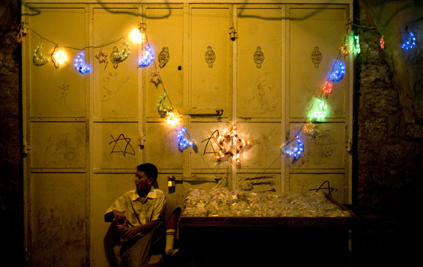 23 August 2009: Jerusalem, Israel: A Palestinian youth sits next to festive light