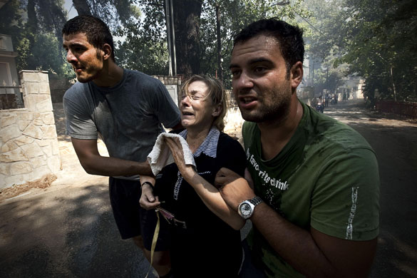 athens update: Two men escort a woman who does not want to leave her burning house