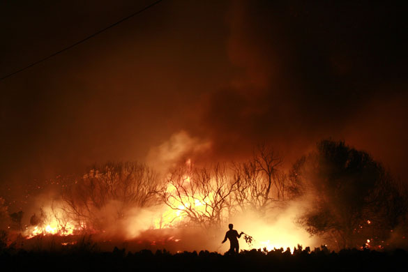 athens update: A volunteer tries to extinguish a forest fire in the village of Kato Souli