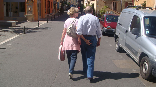 Age Concern Photography: A woman pats her elderly partners bottom as they walk away