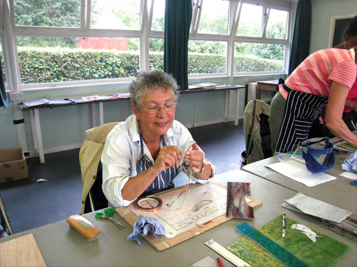 Age Concern Photography: An elderly woman sits at a table doing craft work