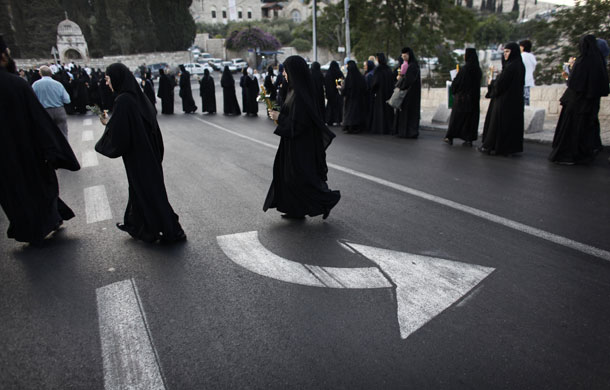 24 hours in pictures: Greek Orthodox nuns hold candles before walking in a procession