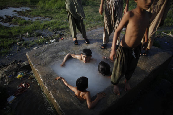 24 hours in pictures: Islamabad Pakistan: Boys in a water reservoir in an Afghan refugee camp 