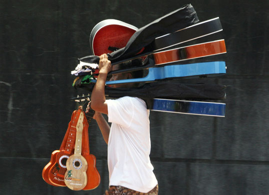 24 hours in pictures: Manila, Phillippines: A man carries guitars to sell along a street