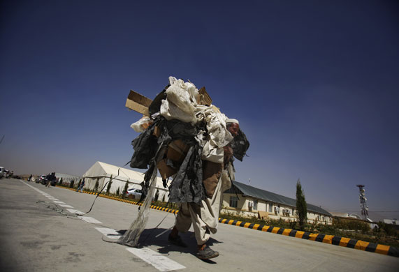 24 hours in pictures: Kabul, Afghanistan: A worker carries rubbish out of the Election Commission