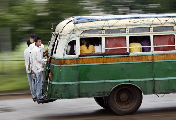 24 hours in pictures : Men stand on the back of a bus in Burma 