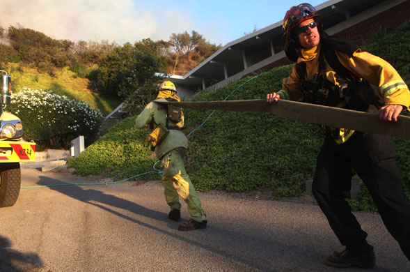 California wildfires: Firefighters pull a firehose as they monitor a back fire in La Crescenta
