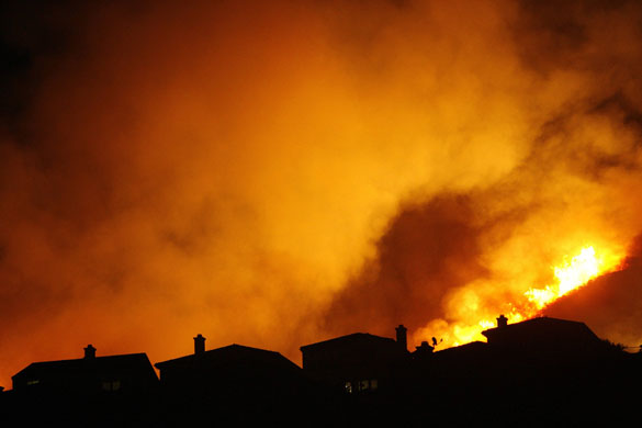 California wildfires: Roofs are silhouetted against the burning hills of a Station Fire