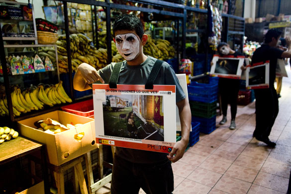 24 hours in pictures: San Salvador, El Salvador: Mimes carry pictures in a market