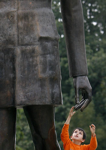 24 hours in pictures: Bucharest, Romania: A child touches a statue of General Charles de Gaulle