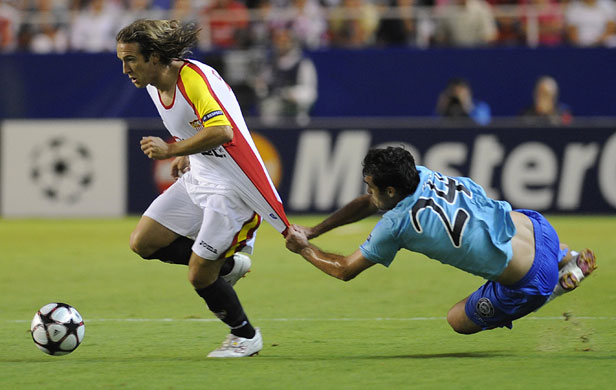 1 wed champions league: Unirea's defender Vasile Maftei clings on to Sevilla's Diego Capel 