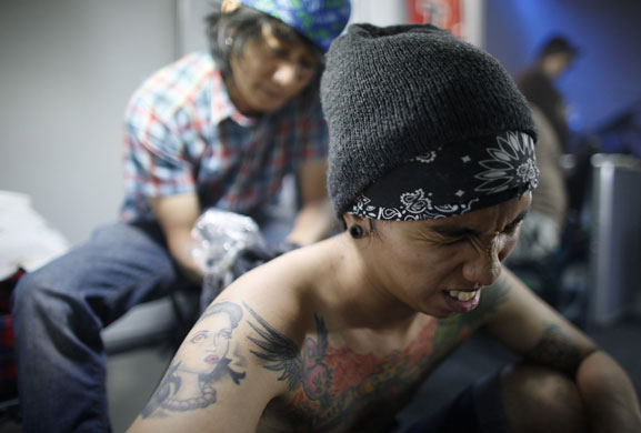 24 hours in pictures: A man reacts as a tattoo artist works on his back in Manila
