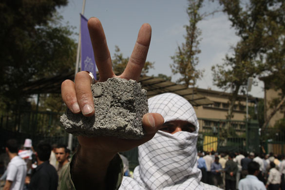 iran protests : An Iranian student holds a stone in an oppostion protest rally