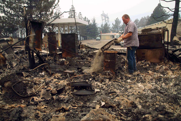 Wildfires California: A man sifts through the burned-out remains of a county structure near Acton